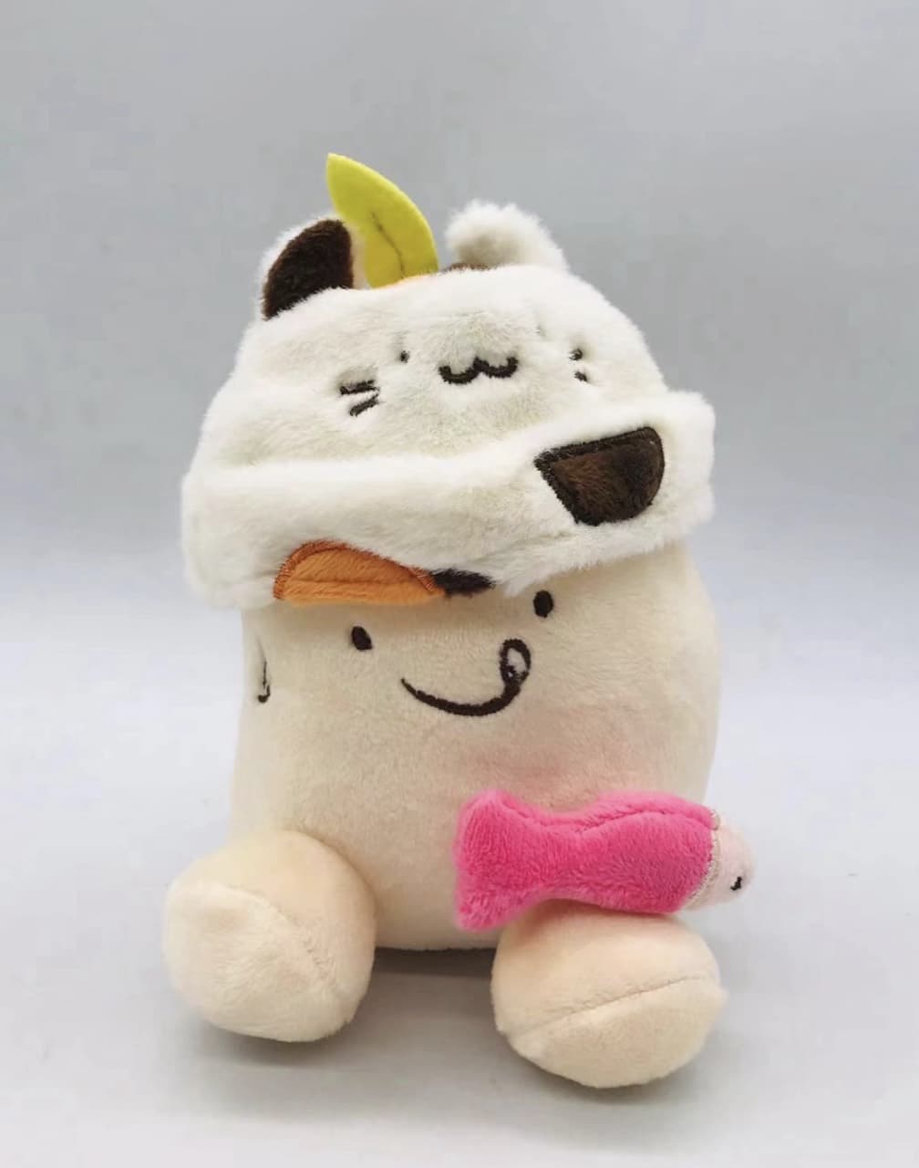 Cat plush toy in a hood holding a fish